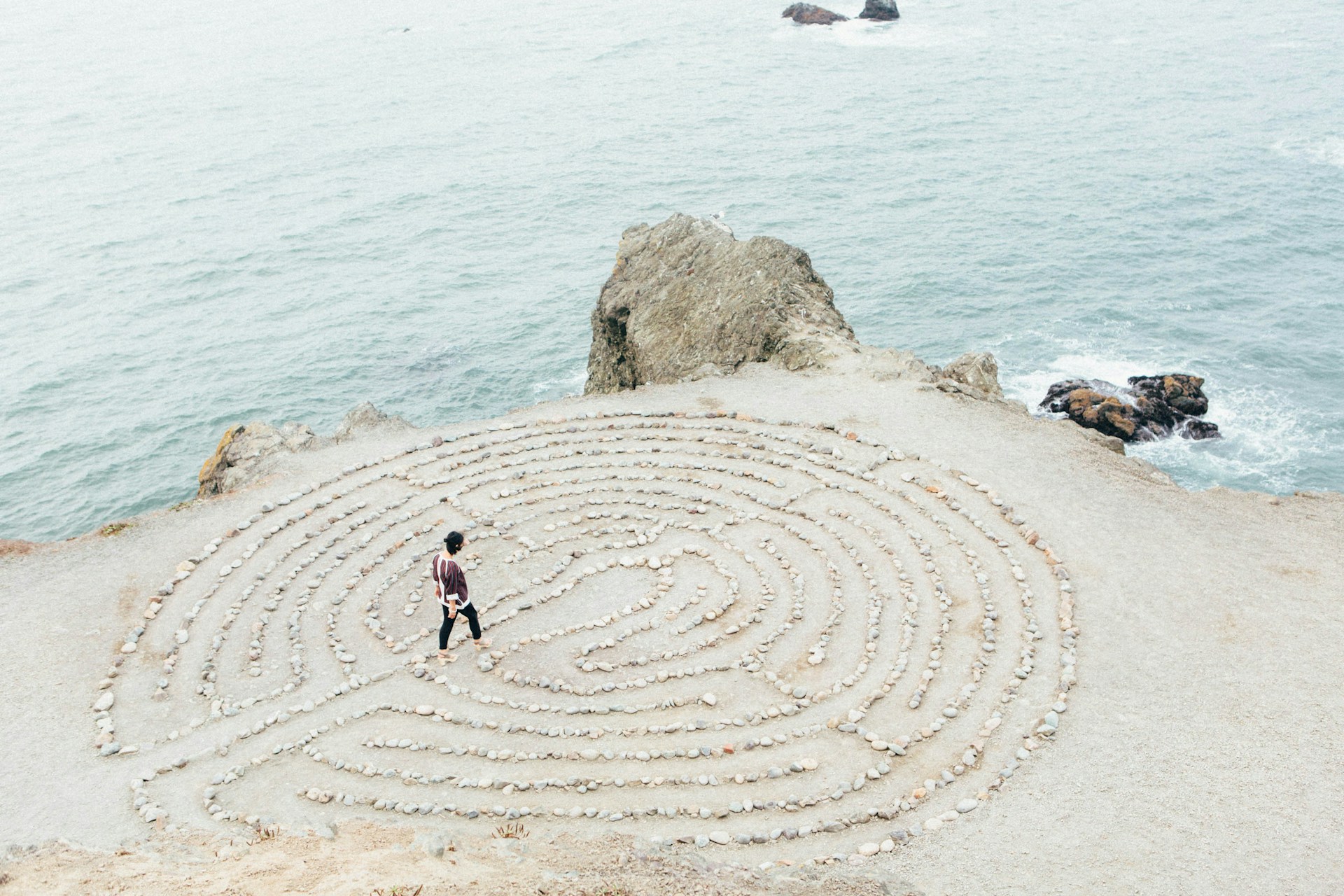 photo of woman walking through a circular sand maze by Ashley Batz for Unsplash